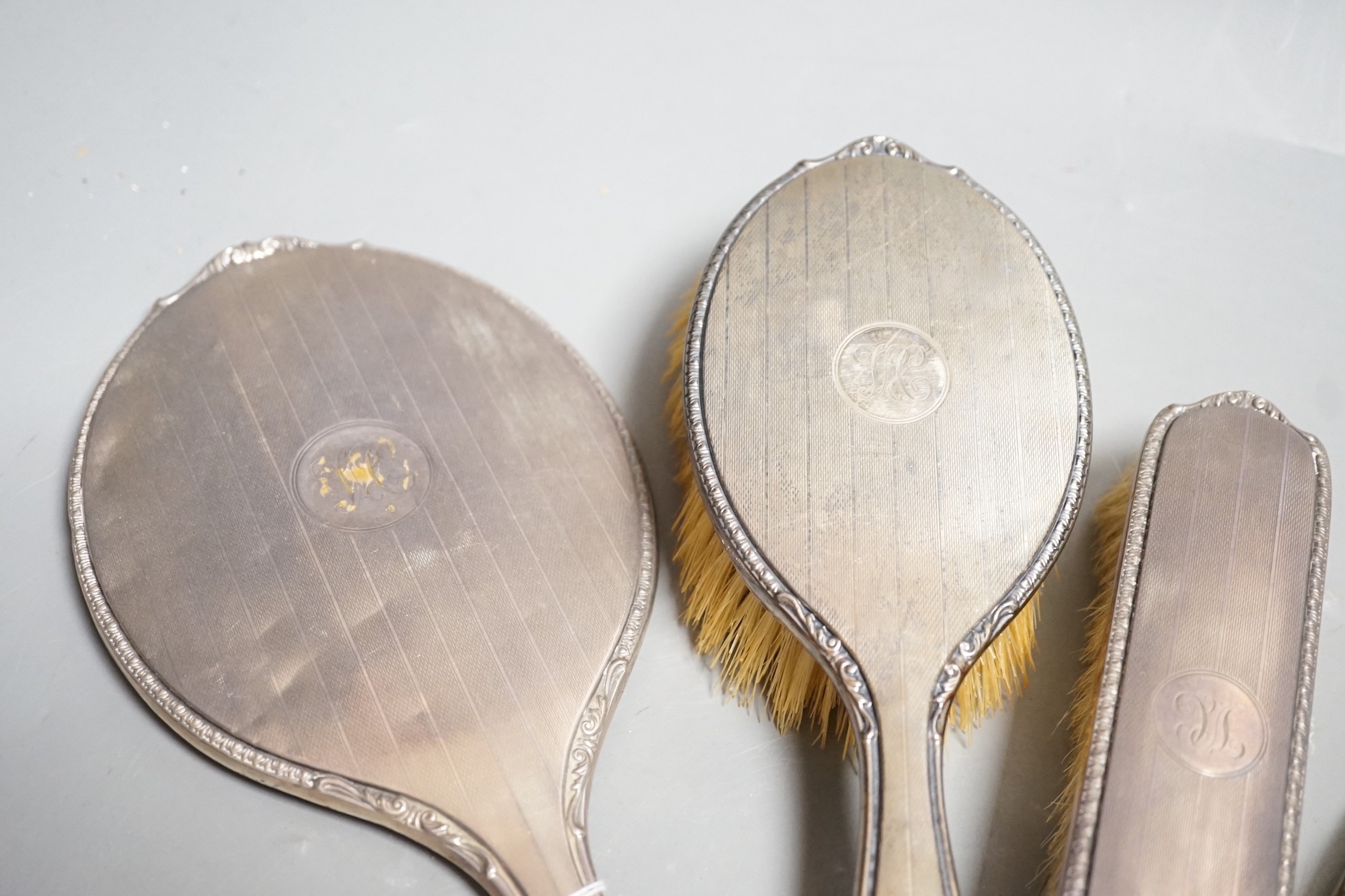 A George V silver mounted hand mirror and similar hair and clothes brush, Adie Bros. Birmingham, 1925 and a silver mounted nail buffer.